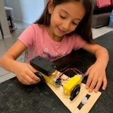 Menina montando um carrinho de madeira com motor e fios