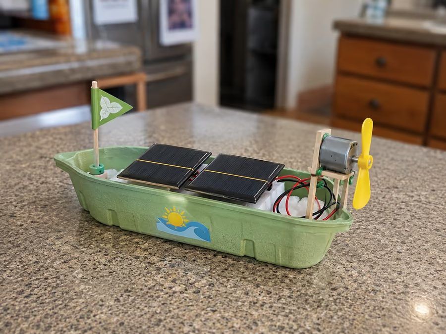 Barco solar em bandeja verde, com painéis solares e hélice