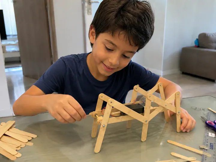 Menino montando um robô andador de palitos de picolé